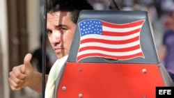 Un hombre saluda desde una bicitaxi con la bandera de EEUU en una calle de La Habana.