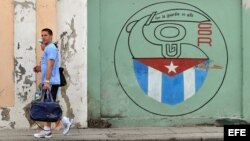 Una pareja camina junto a un cartel con el emblema de los Comités de Defensa de la Revolución en La Habana.