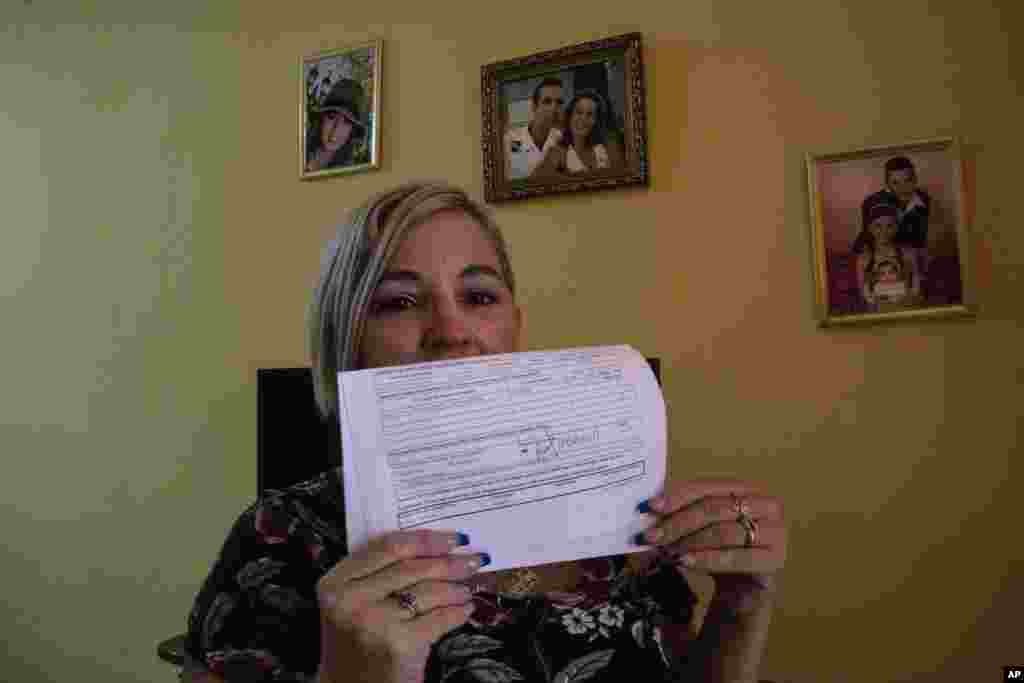 Danmara Triana muestra el documento, fechado en septiembre de 2017, empleado por su esposo para iniciar el proceso de reunificación familiar.  (AP Foto/Ramón Espinosa)